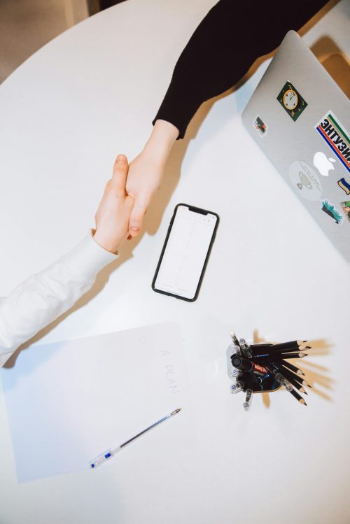 Een witte tafel met een iphone en handen die schudden